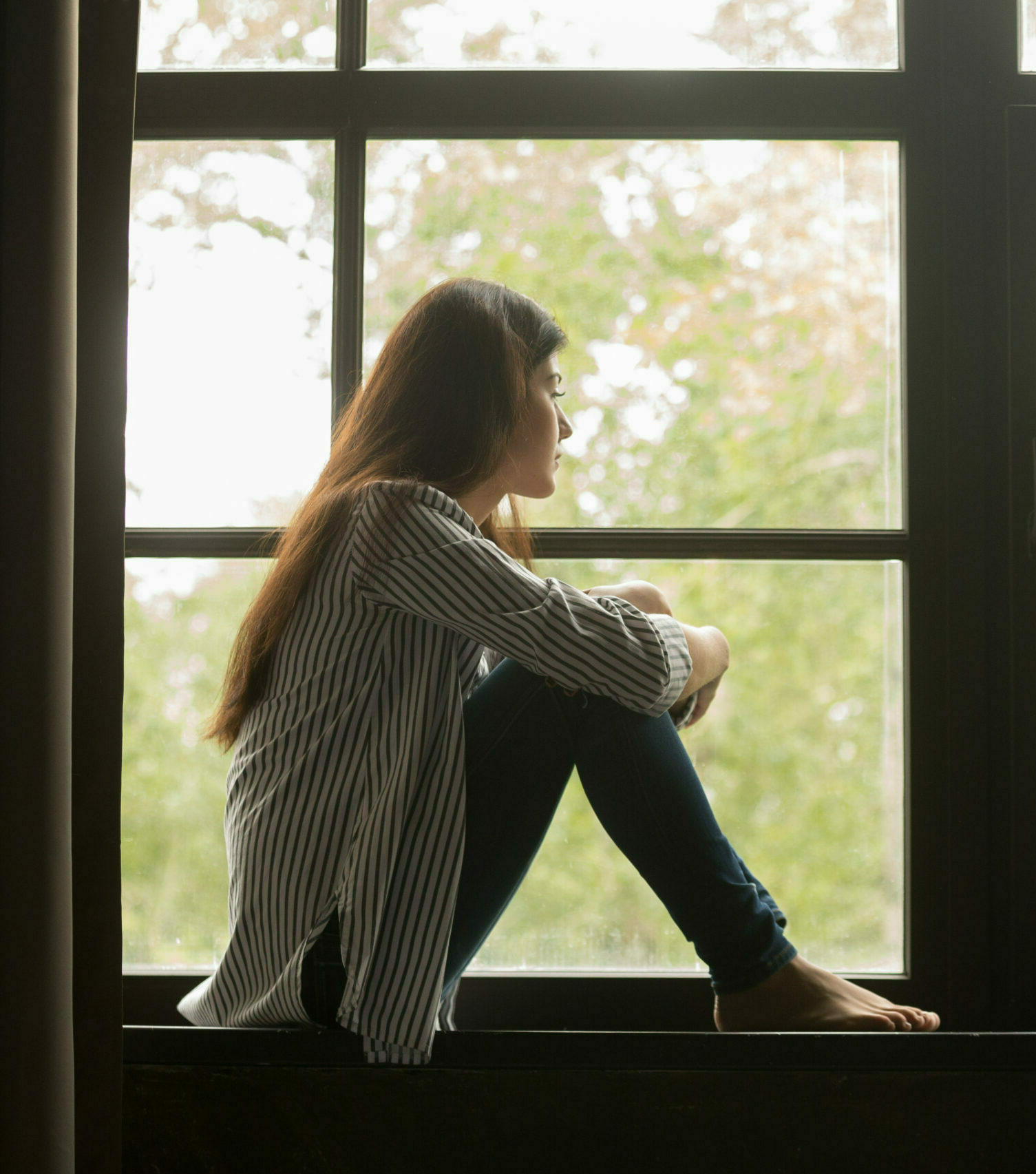 Teenagepige sidder i et vindue